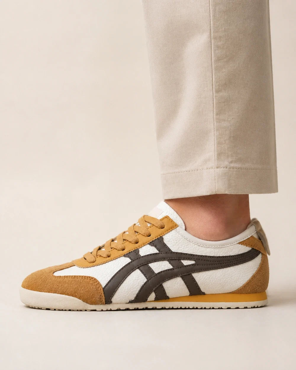 Lateral worn profile of brown-yellow retro panel sneakers.